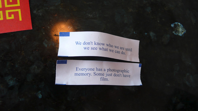 Two fortunes from cookies at a chinese restaurant. The fortunes read: [We don't know who we are until we see what we can do.] and [Every one has a photographic memory. Some just don't have film.]